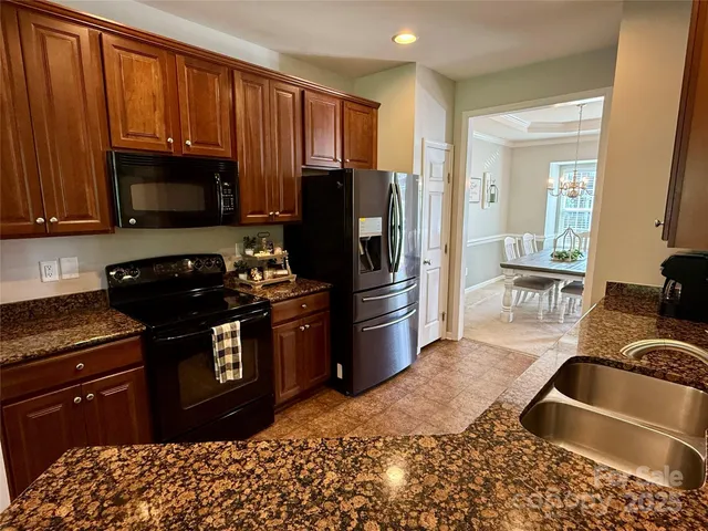 a kitchen with granite countertop wooden cabinets a stove a oven and a refrigerator with wooden floor