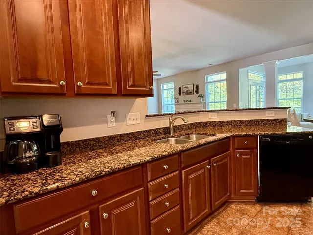 a kitchen with granite countertop stainless steel appliances a sink stove and cabinets