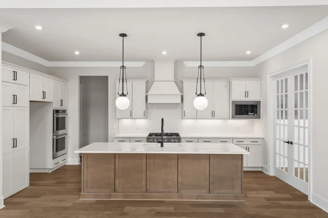 a kitchen with stainless steel appliances granite countertop a sink a refrigerator a stove and white cabinets with wooden floor