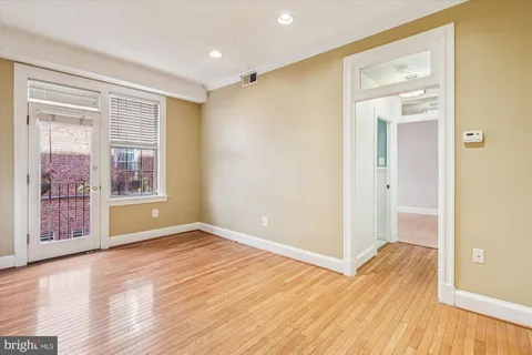 a view of an empty room with wooden floor and a window