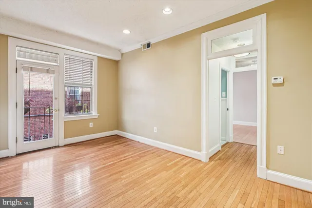a view of an empty room with wooden floor and a window