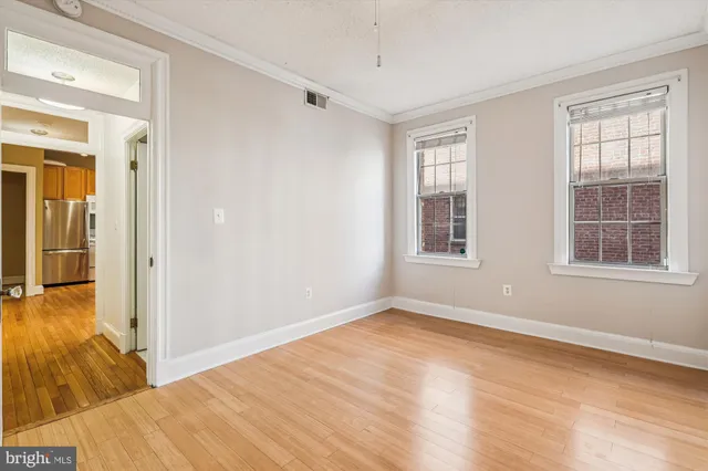 a view of empty room with wooden floor and fan