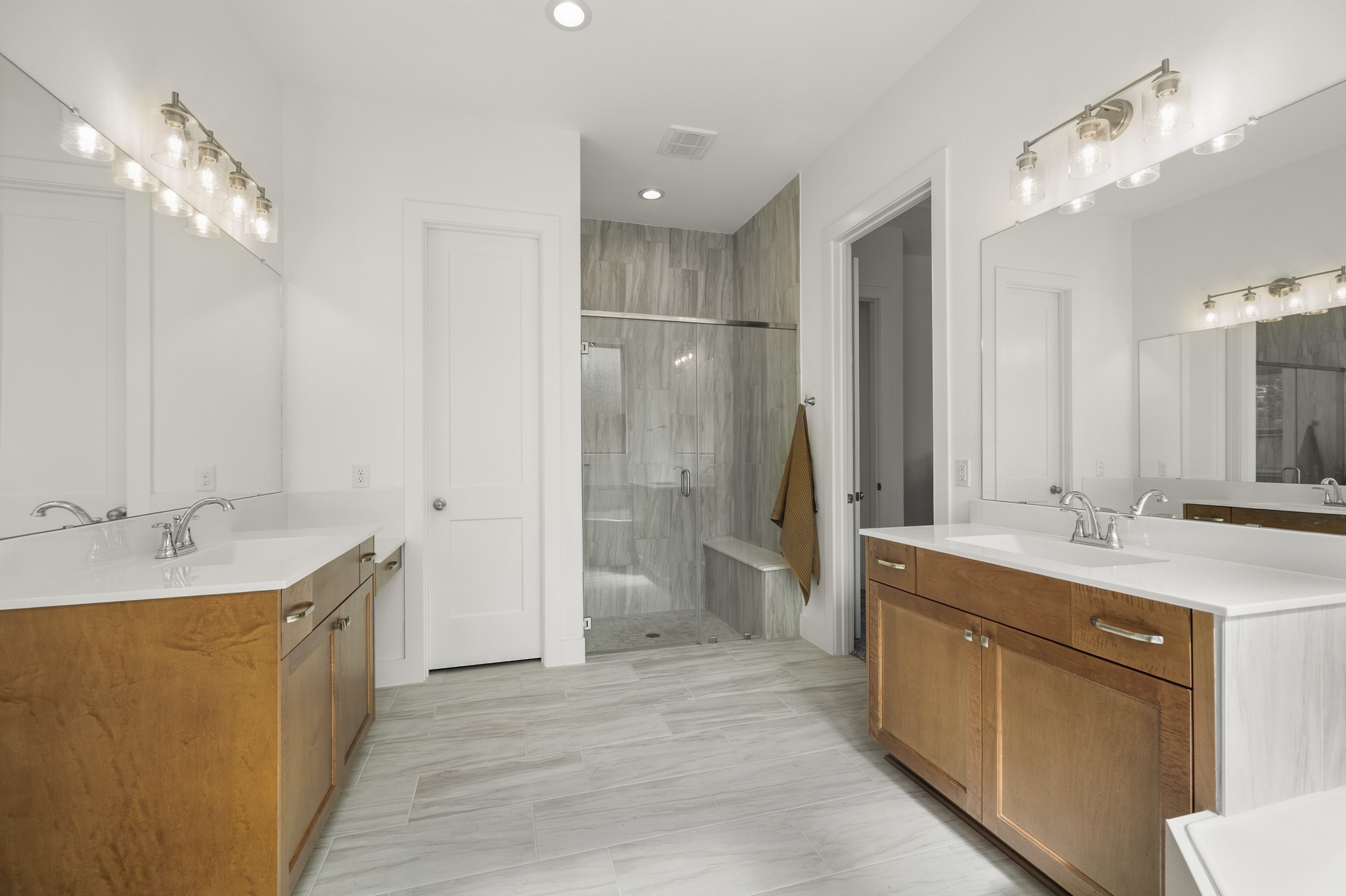 7403 Hanover Lane Katy, TX 77493 - Photo 20 of 46 Indulge in the spaciousness of this primary bathroom featuring large dual vanities with wood cabinets, quartz countertops, and large mirrors, and a walk-in shower with mud-set tile and frameless glass surround!