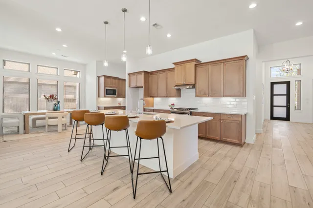 a kitchen with stainless steel appliances kitchen island granite countertop a stove a sink a dining table and chairs with wooden floor