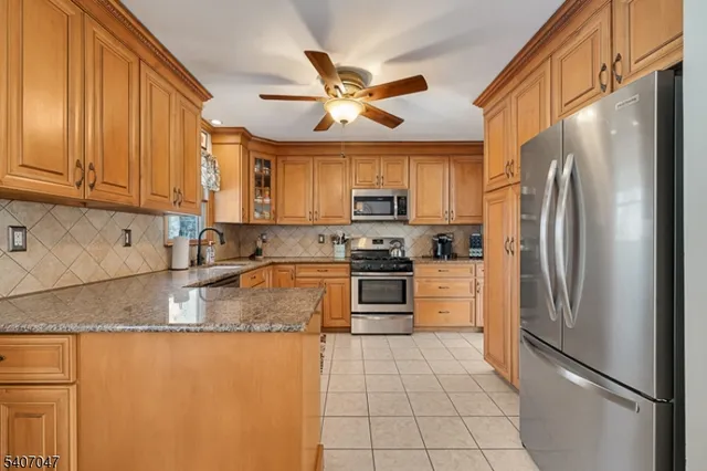 a kitchen with granite countertop a refrigerator a sink a stove and cabinets