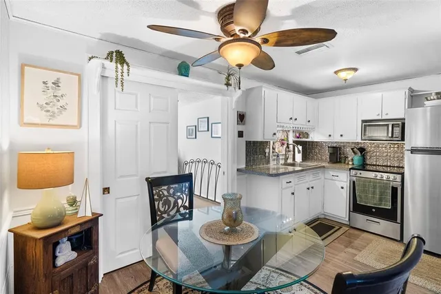 a kitchen with stainless steel appliances granite countertop a stove a refrigerator a sink a dining table and chairs with wooden floor