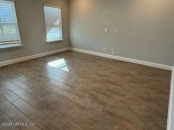 an empty room with wooden floor and windows
