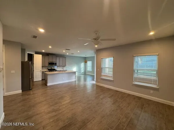 a large kitchen with kitchen island granite countertop a refrigerator a sink a stove and white cabinets