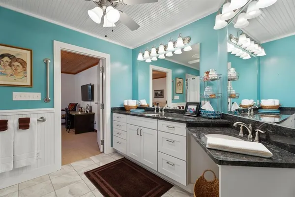 a spacious en suite bathroom with a granite countertop sink a light fixture and a mirror