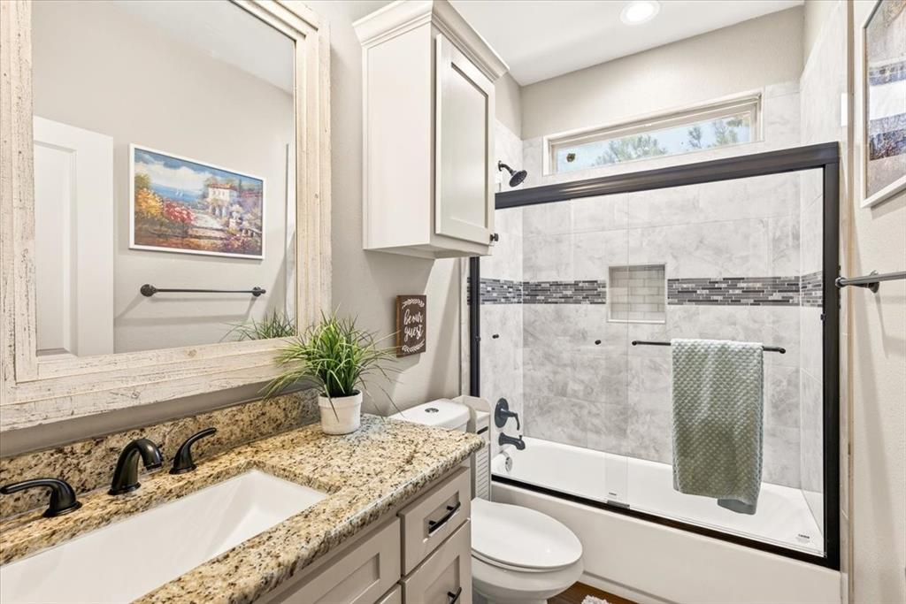 531 VZ County Road Eustace, TX 75124 - Photo 19 of 35 Bathroom featuring a granite vanity, white cabinetry, undermount sink, and a tiled shower-bathtub combination with a glass enclosure