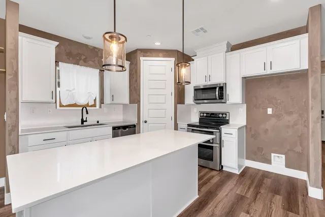 a kitchen with a refrigerator a stove and wooden floor