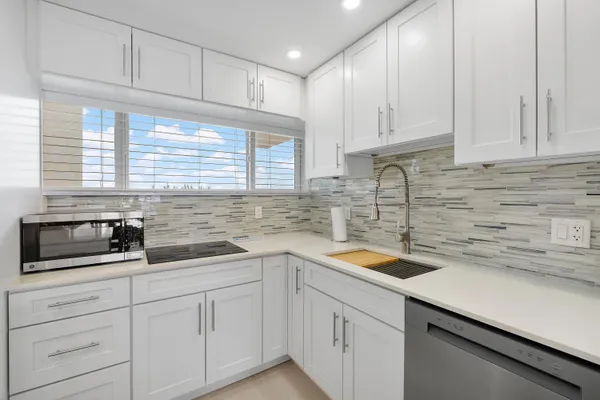 a kitchen with white cabinets white appliances and sink
