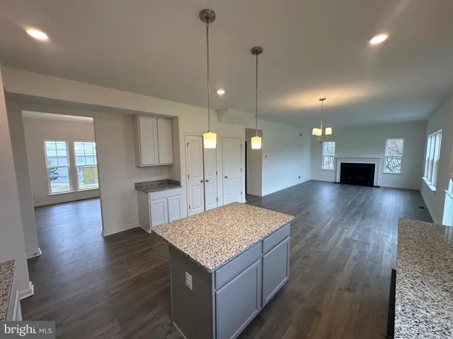 a kitchen with kitchen island granite countertop wooden floors and a fireplace