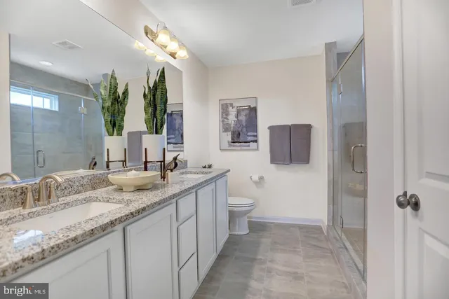 a bathroom with a granite countertop sink mirror vanity and toilet