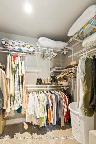 a spacious bedroom with a bed a dresser and a chandelier