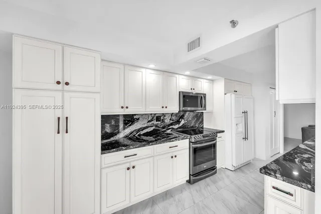 a kitchen with stainless steel appliances a refrigerator stove and white cabinets