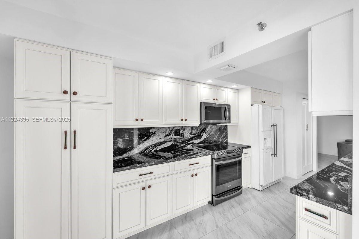 a kitchen with stainless steel appliances a refrigerator stove and white cabinets