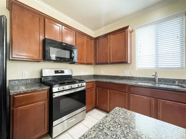 a kitchen with granite countertop wooden cabinets stainless steel appliances and a window
