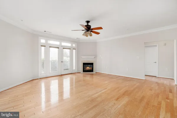 a view of an empty room with window and chandelier fan