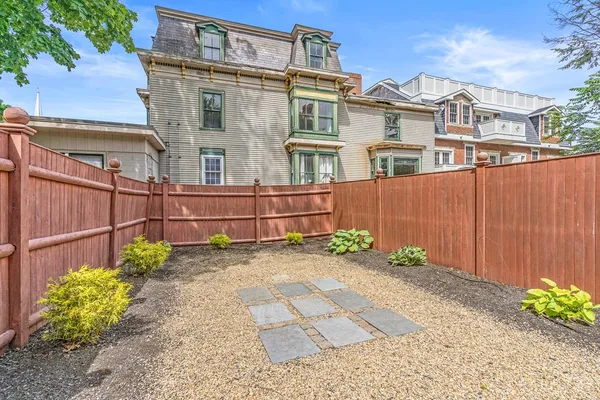 a view of a house with a backyard and wooden fence