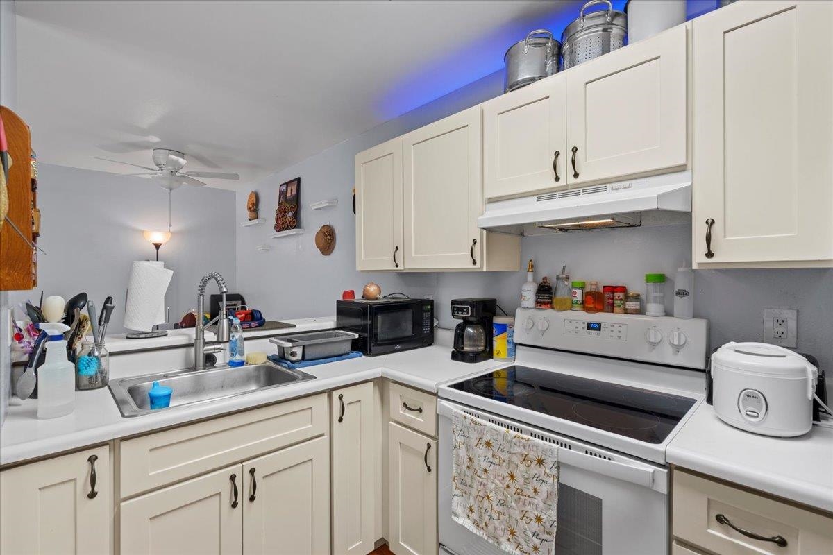 480 Kenolio Road, Unit 1103 Kihei, HI 96753 - Photo 10 of 32 a kitchen with white cabinets and white appliances