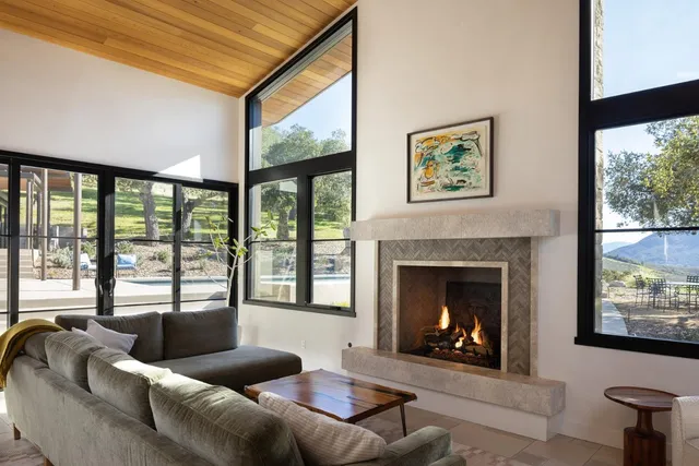 a living room with furniture a fireplace and a large window