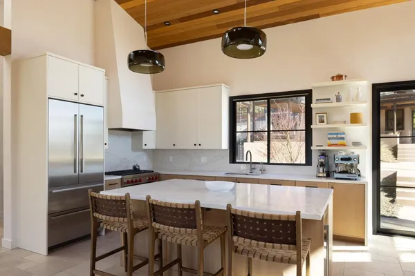 a kitchen with stainless steel appliances kitchen island granite countertop a table chairs in it and white cabinets