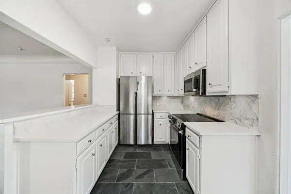 a kitchen with white cabinets and refrigerator