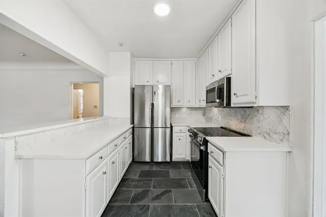 a kitchen with white cabinets and refrigerator