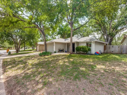 a view of a house with a yard and large tree