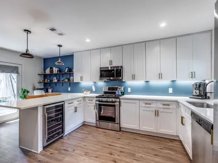 a kitchen with stainless steel appliances granite countertop a stove top oven a sink and dishwasher with white cabinets