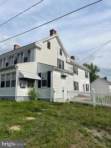 a view of a white house next to a yard