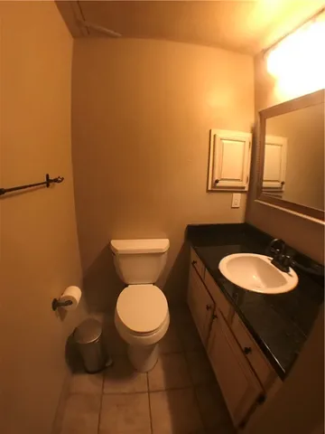 a bathroom with a granite countertop toilet and a sink