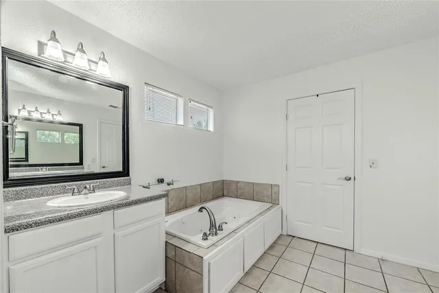 a bathroom with a granite countertop sink a mirror and bathtub