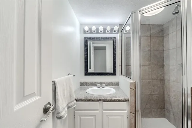 a bathroom with a granite countertop sink a mirror and a shower