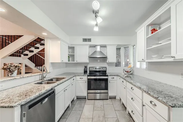 a kitchen with granite countertop stainless steel appliances sink stove and cabinets