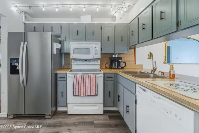 a kitchen with stainless steel appliances granite countertop a refrigerator a sink and white cabinets