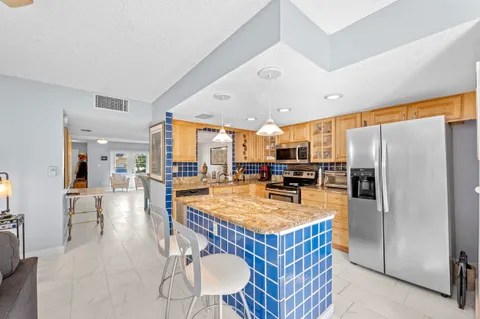 a kitchen with stainless steel appliances granite countertop a refrigerator a oven a sink a dining table and chairs