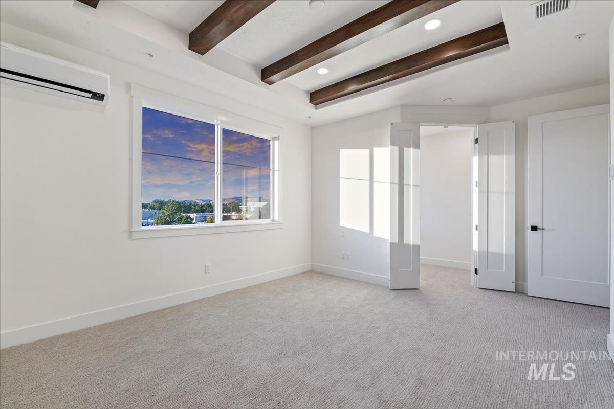 3249 West Moore Street Boise, ID 83702 - Photo 14 of 35 Unfurnished room featuring light carpet, a wall mounted air conditioner, and beam ceiling