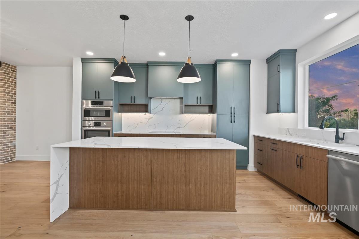 3249 West Moore Street Boise, ID 83702 - Photo 4 of 35 Kitchen featuring stainless steel appliances, light stone countertops, a center island, hanging light fixtures, and light wood-style flooring