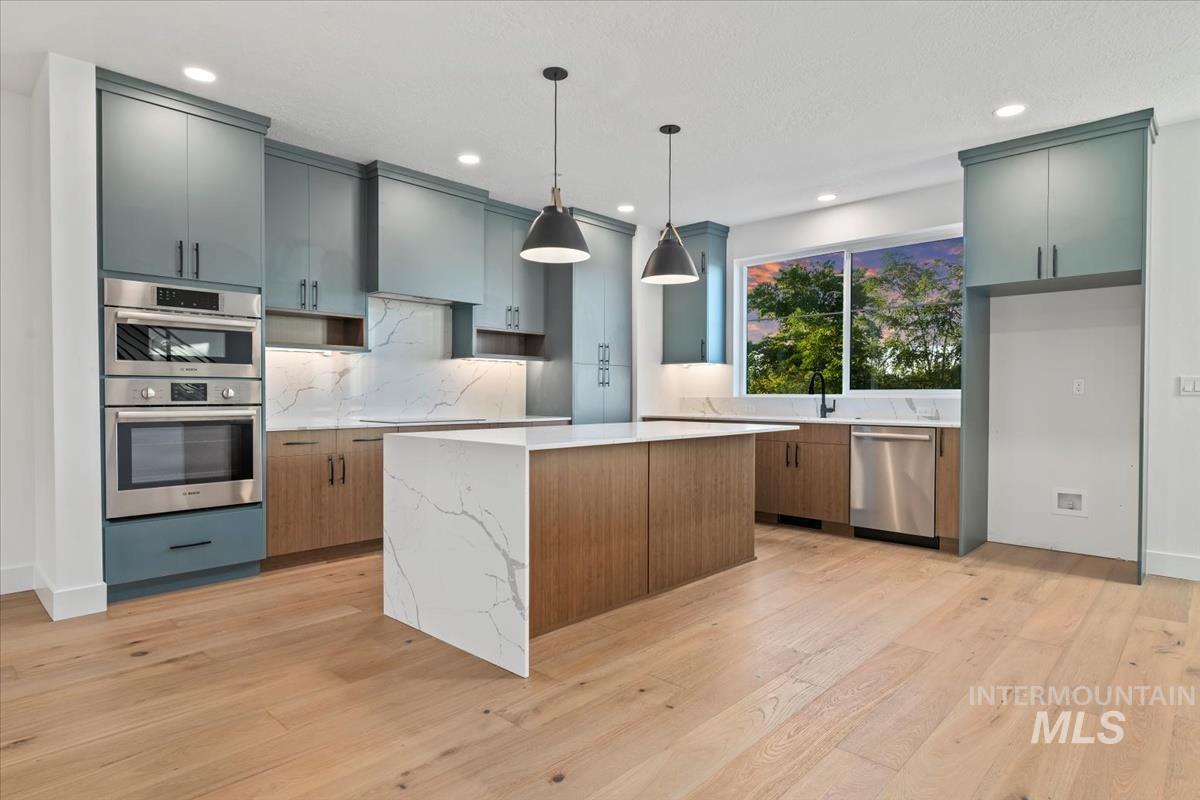 3249 West Moore Street Boise, ID 83702 - Photo 5 of 35 Kitchen with a kitchen island, decorative light fixtures, light wood finished floors, light stone counters, and stainless steel appliances