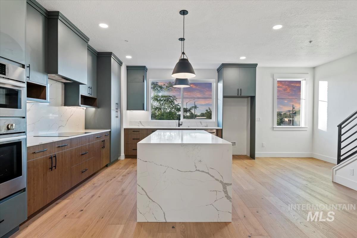 3249 West Moore Street Boise, ID 83702 - Photo 6 of 35 Kitchen featuring a center island, light stone counters, pendant lighting, light wood-style flooring, and recessed lighting