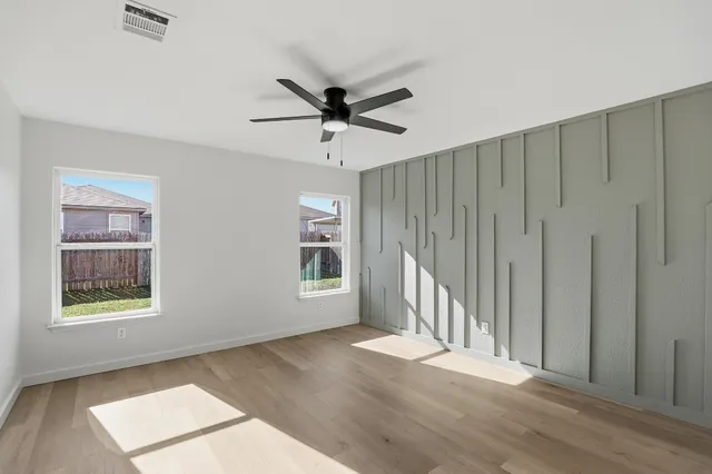 a view of empty room with wooden floor and fan
