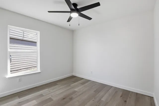 an empty room with a window and a fan