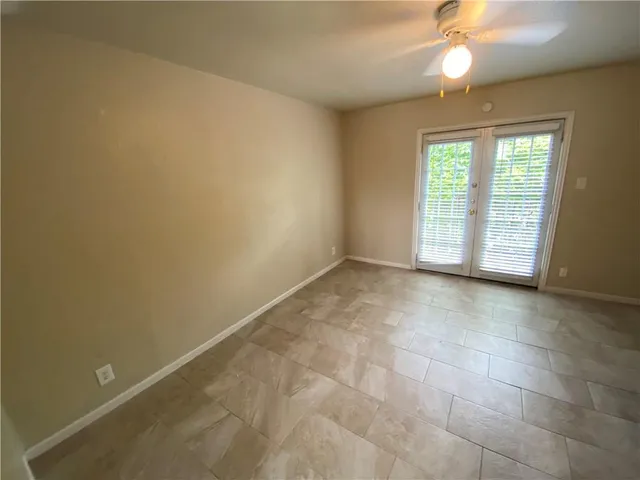 an empty room with windows and chandelier fan