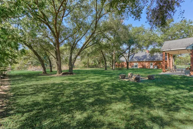 a view of backyard with huge green field and trees
