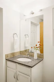 a bathroom with a granite countertop sink and a mirror