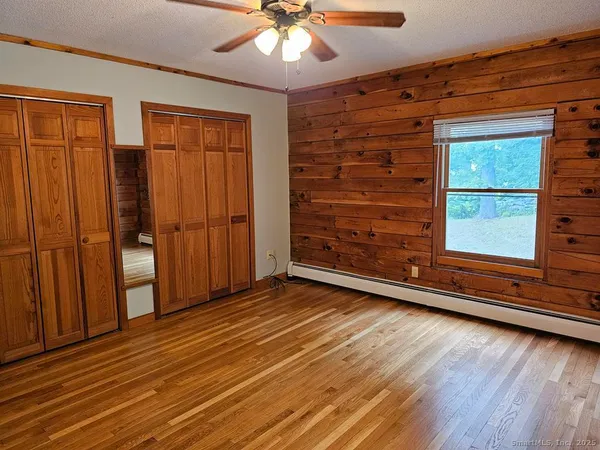 an empty room with wooden floor closet and windows