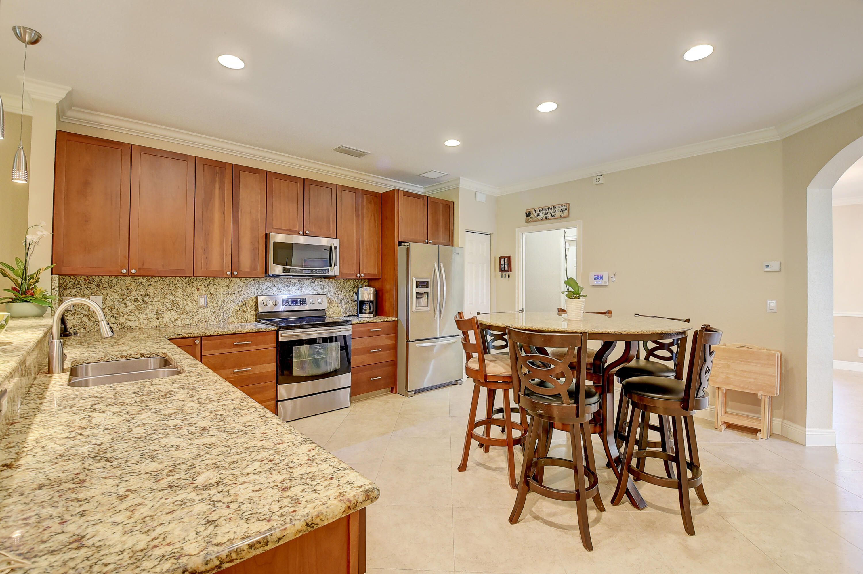 215 Gulfstream Boulevard Boynton Beach, FL 33435 - Photo 12 of 39 a kitchen with stainless steel appliances granite countertop a table chairs sink refrigerator and cabinets