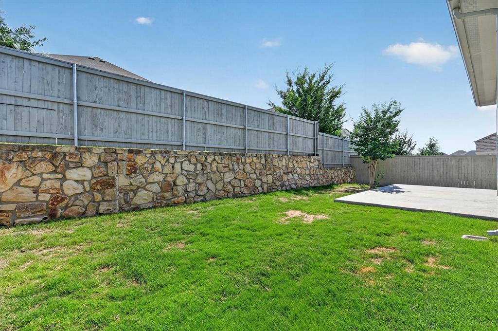 2237 Pika Road Northlake, TX 76247 - Photo 37 of 37 Expansive backyard featuring a stone retaining wall, wood privacy fencing, a concrete patio, and a grass lawn
